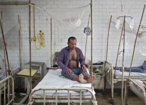 A patient awaits routine check-up as he sits under a mosquito net inside a dengue ward of a government hospital in New Delhi